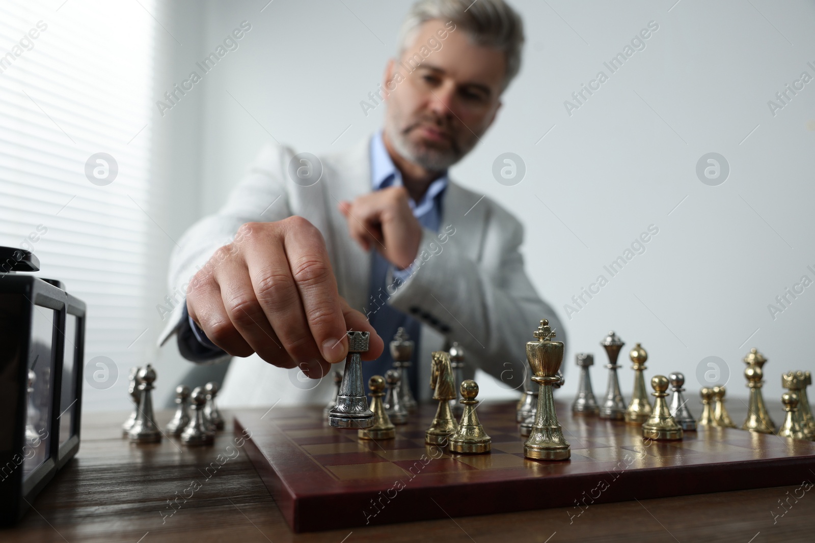 Photo of Man playing chess during tournament at table, selective focus