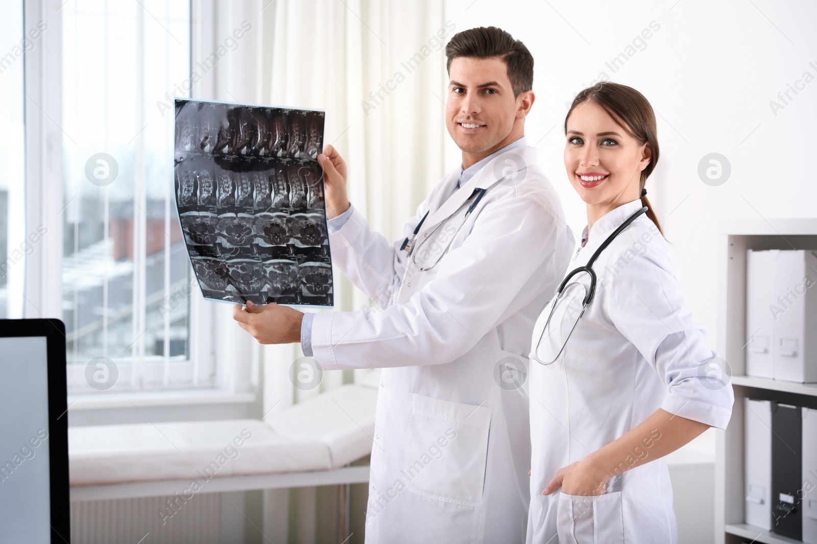 Photo of Orthopedists examining X-ray picture near window in office