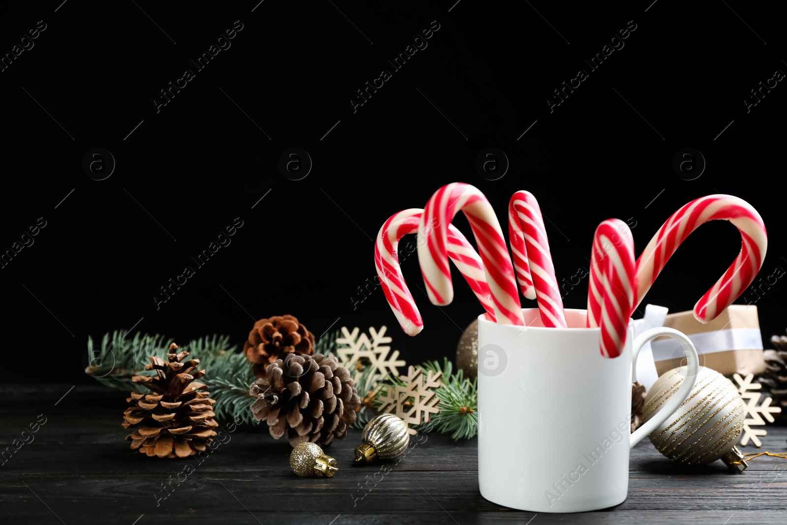 Photo of Many sweet candy canes and Christmas decor on black wooden table