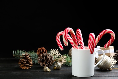 Photo of Many sweet candy canes and Christmas decor on black wooden table