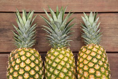 Delicious ripe pineapples on wooden table, flat lay