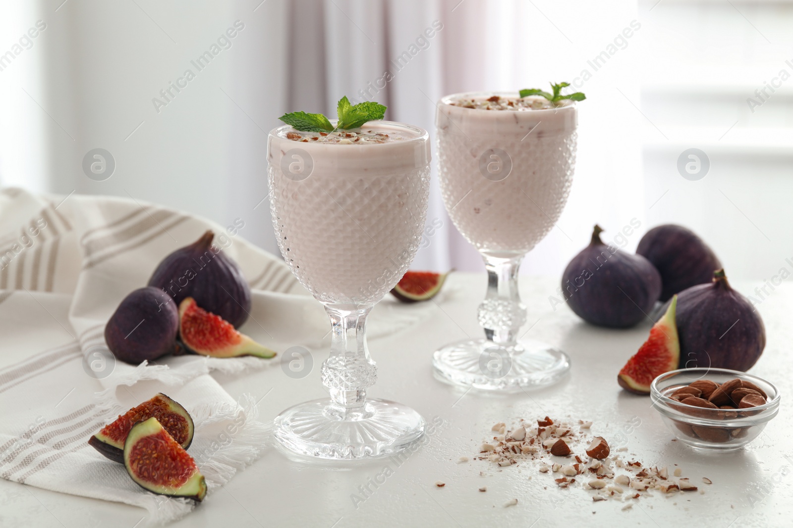 Photo of Delicious fig smoothies in glasses on white table