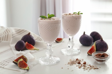 Photo of Delicious fig smoothies in glasses on white table