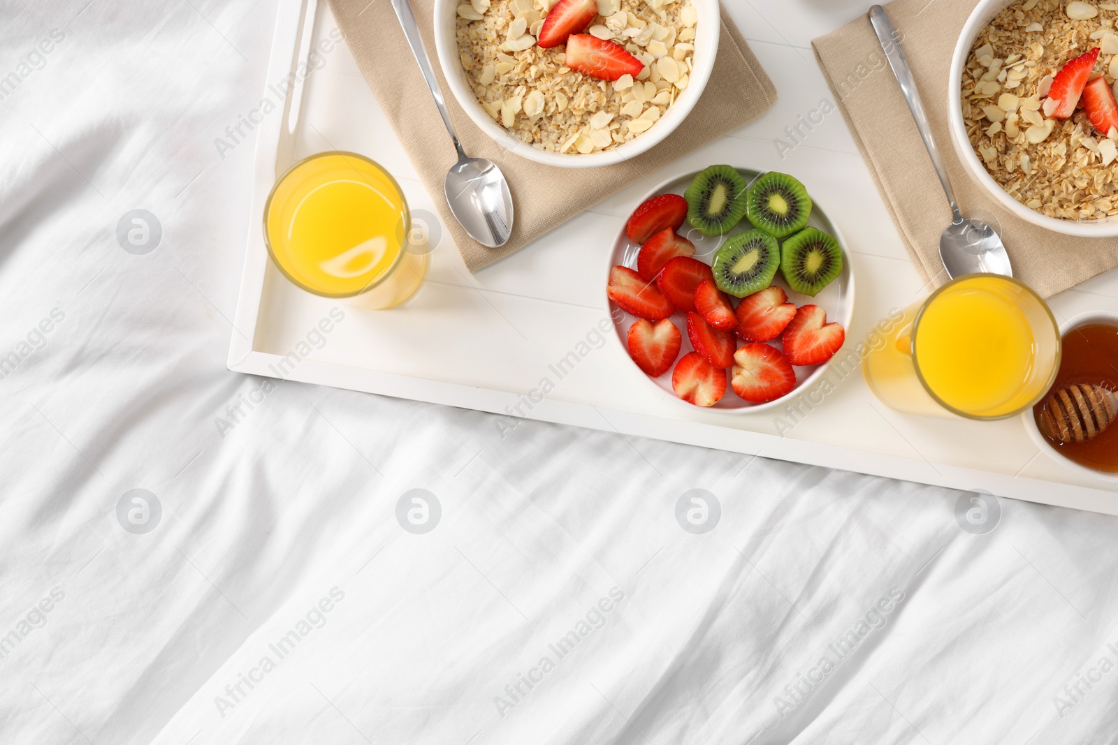 Tasty breakfast served in bed. Oatmeal, juice, fruits and honey on tray, top view. Space for text Photo of Tasty breakfast served in bed. Oatmeal, juice, fruits and honey on tray, top view. Space for text
