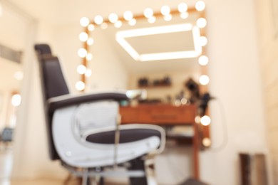 Photo of Blurred view of professional barber chair in hairdressing salon