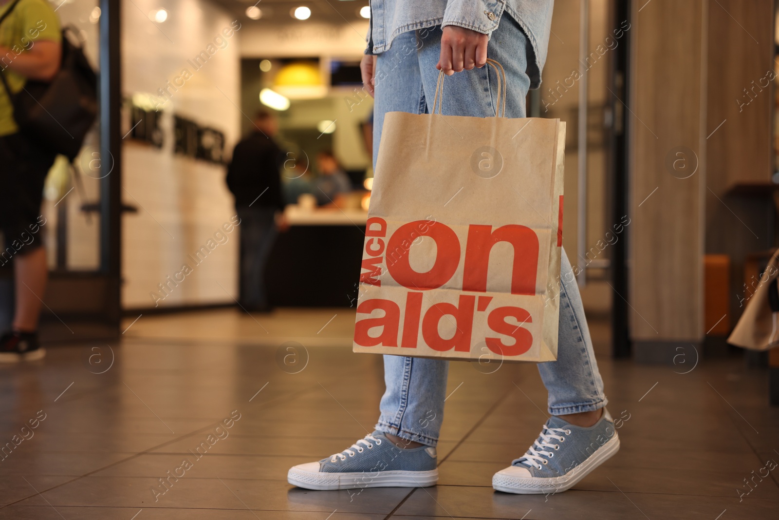 Photo of Lviv, Ukraine - September 26, 2023: Woman with McDonald's paper bag in cafe, closeup. Space for text