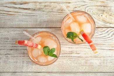 Photo of Glasses of grapefruit cocktails on wooden table, flat lay