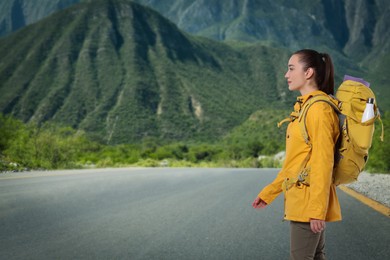 Image of Tourist with backpack on road near mountains