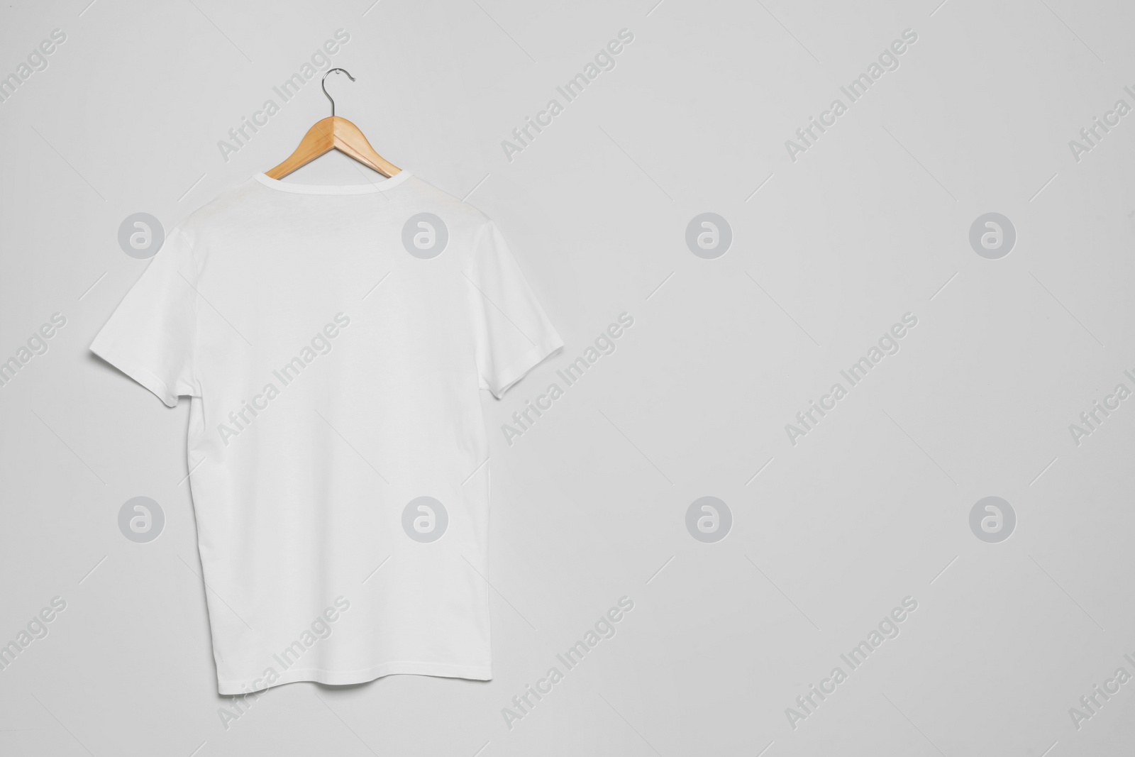 Photo of Hanger with blank t-shirt on gray background. Mock up for design