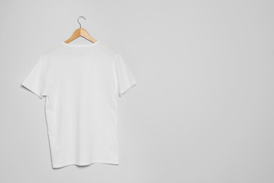 Hanger with blank t-shirt on gray background. Mock up for design