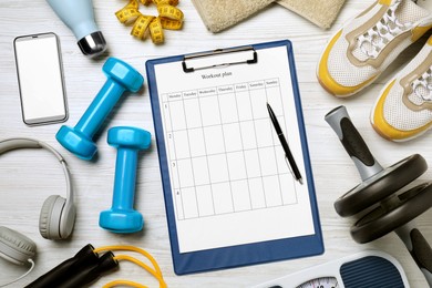 Photo of Clipboard with workout plan, smartphone and sports equipment on white wooden table, flat lay. Personal training