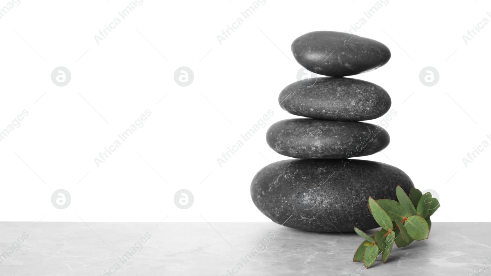 Photo of Stack of spa stones and green leaves on table against white background. Space for text