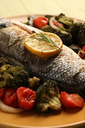 Photo of Delicious baked fish and vegetables on plate, closeup