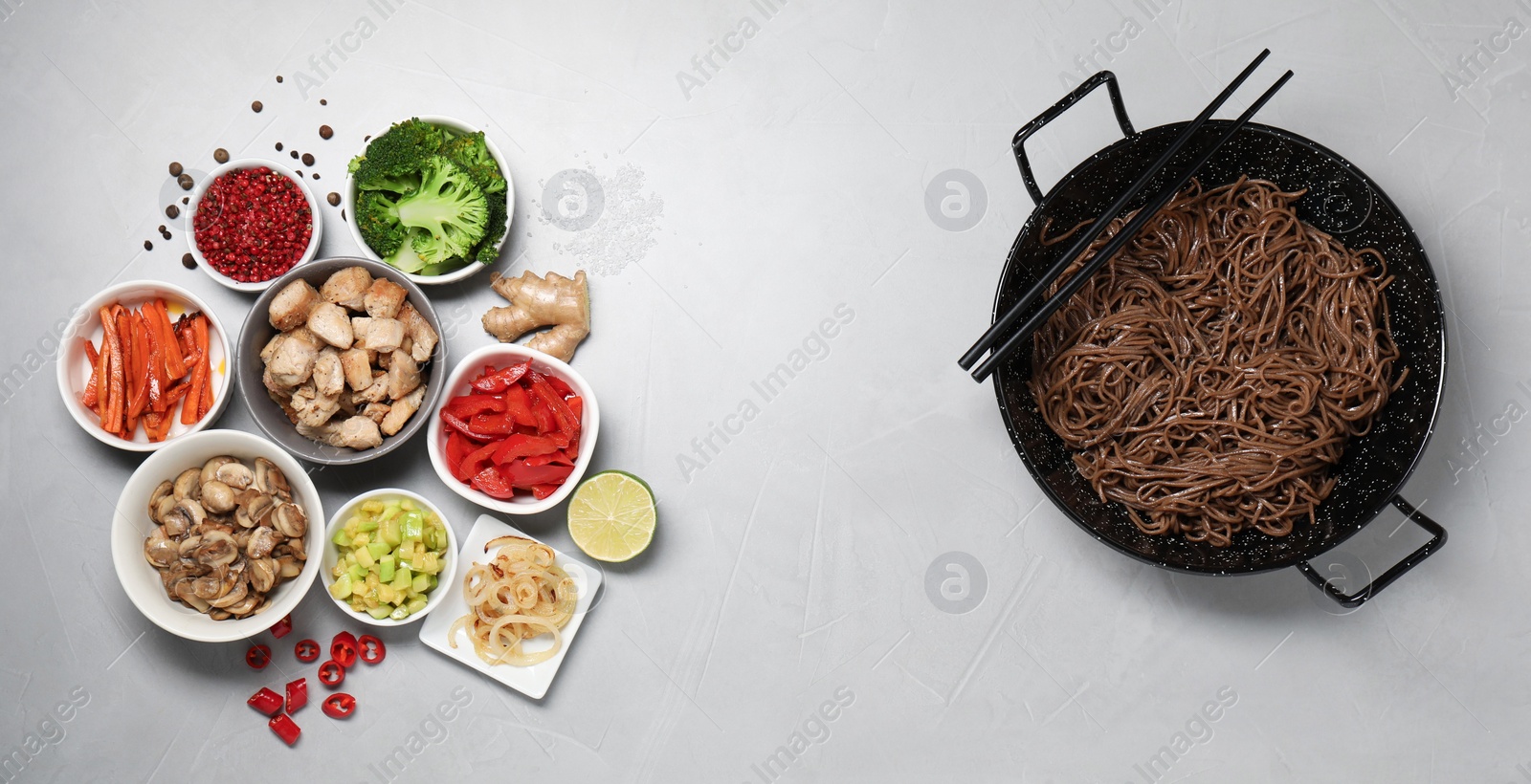 Photo of Wok with noodles, chicken and other products on light grey table, flat lay. Space for text