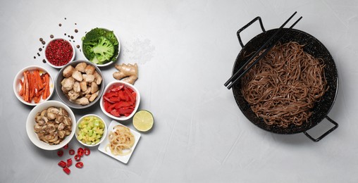 Photo of Wok with noodles, chicken and other products on light grey table, flat lay. Space for text