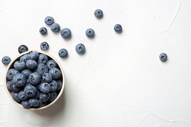 Photo of Crockery with juicy blueberries and space for text on white table, top view