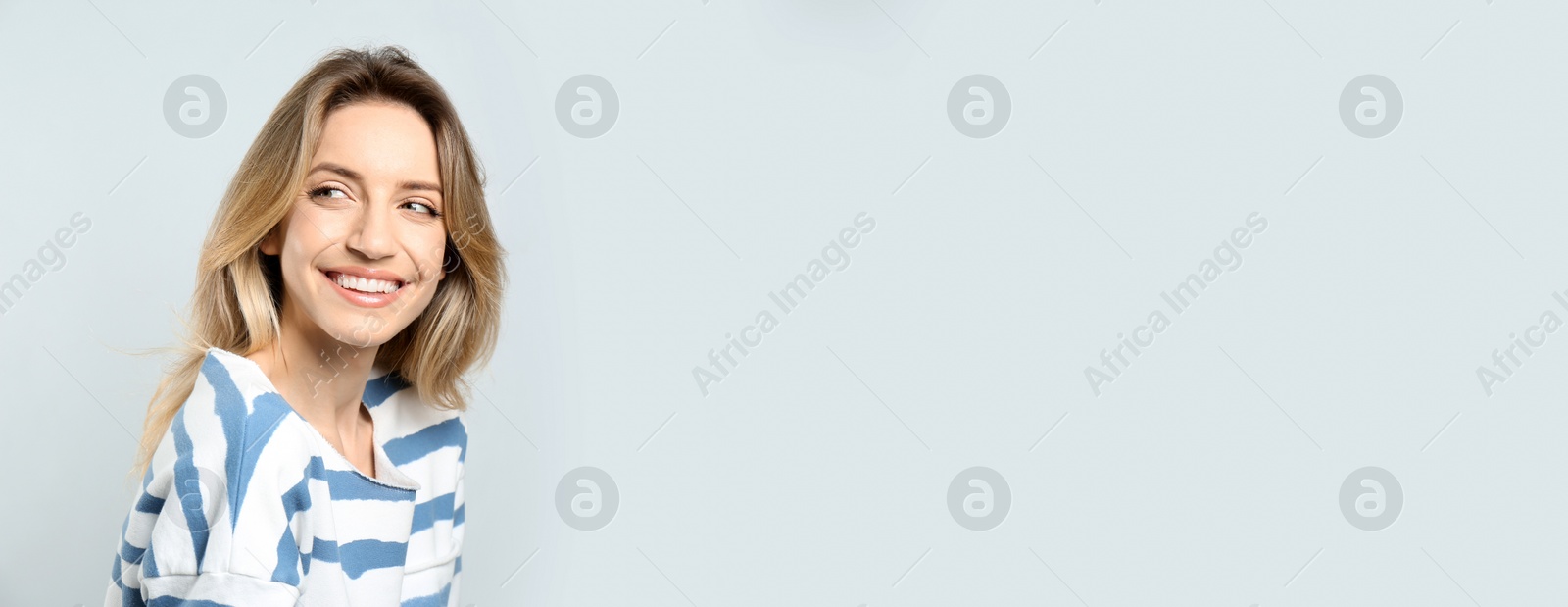 Photo of Portrait of happy young woman with beautiful blonde hair and charming smile on light background. Space for text