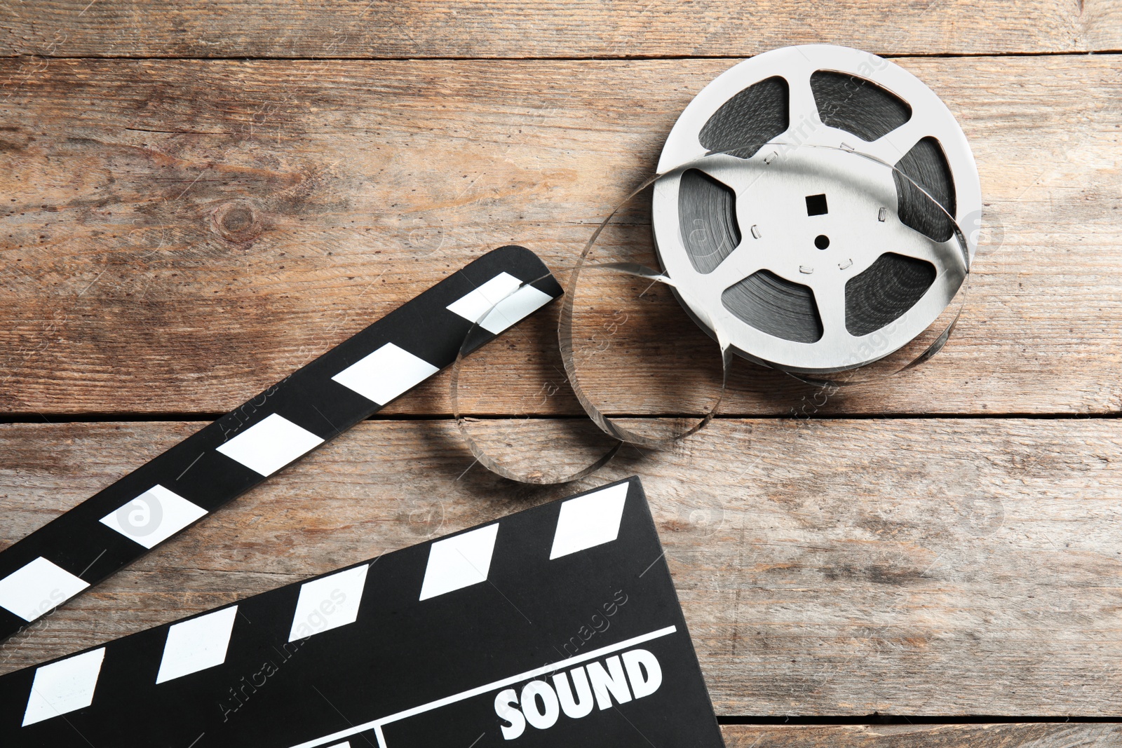 Photo of Clapperboard and reel on wooden background, top view. Cinema production