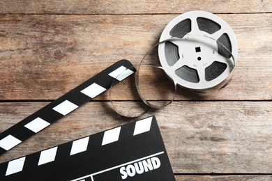 Photo of Clapperboard and reel on wooden background, top view. Cinema production