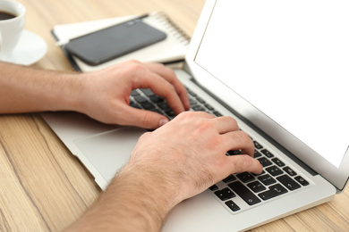 Photo of Man working with modern laptop at wooden table, closeup