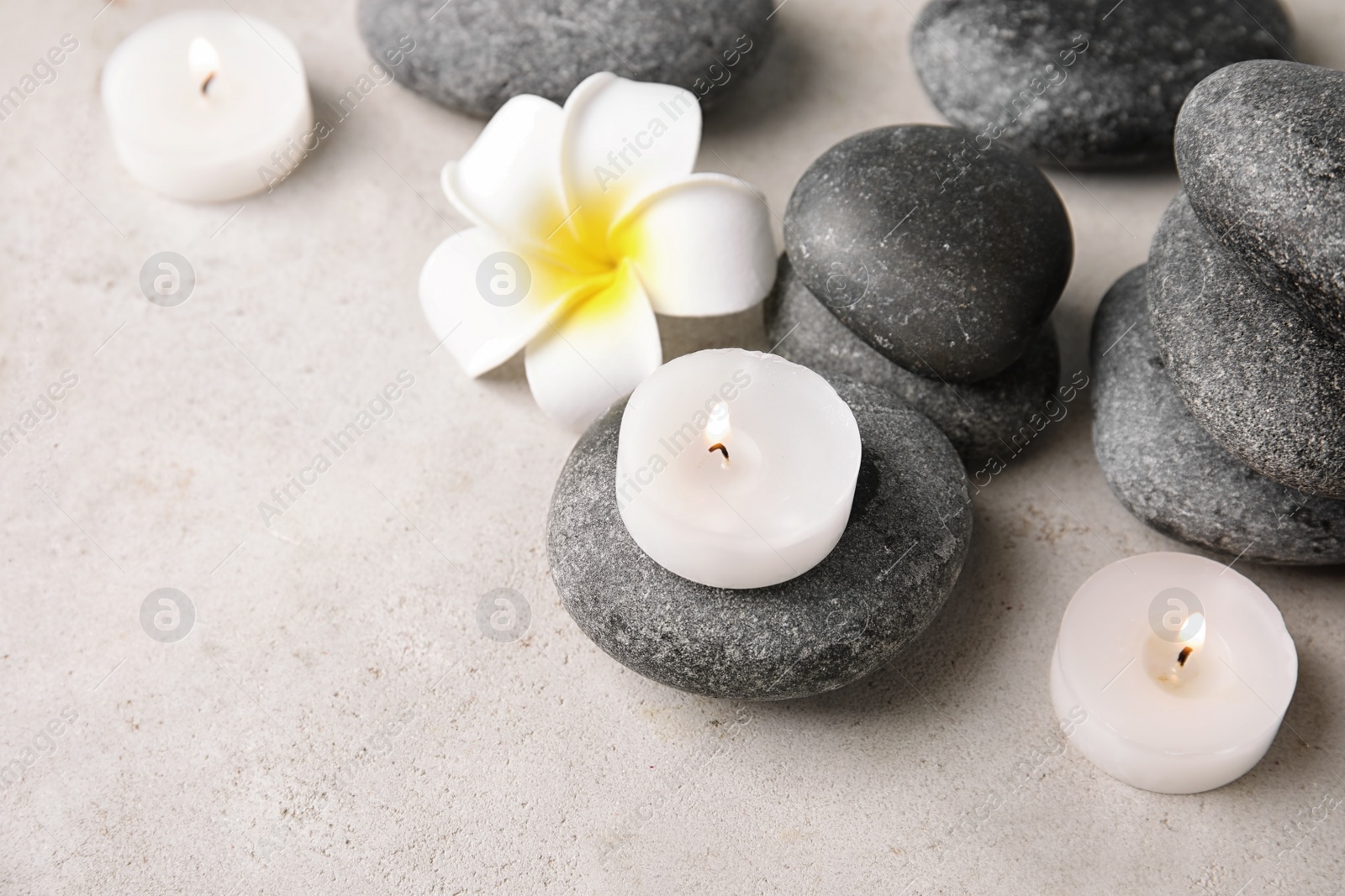 Photo of Beautiful spa composition with candles and stones on table, space for text