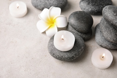 Photo of Beautiful spa composition with candles and stones on table, space for text