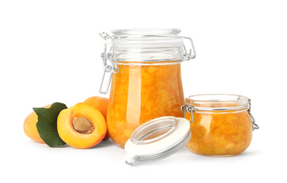 Jars of apricot jam and fresh fruits on white background