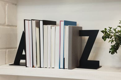 Decorative bookends with books and houseplant on shelf indoors