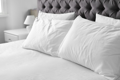 Photo of Comfortable bed with white linen and pillows at home