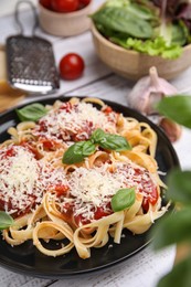 Delicious pasta with tomato sauce, basil and parmesan cheese on white wooden table, closeup