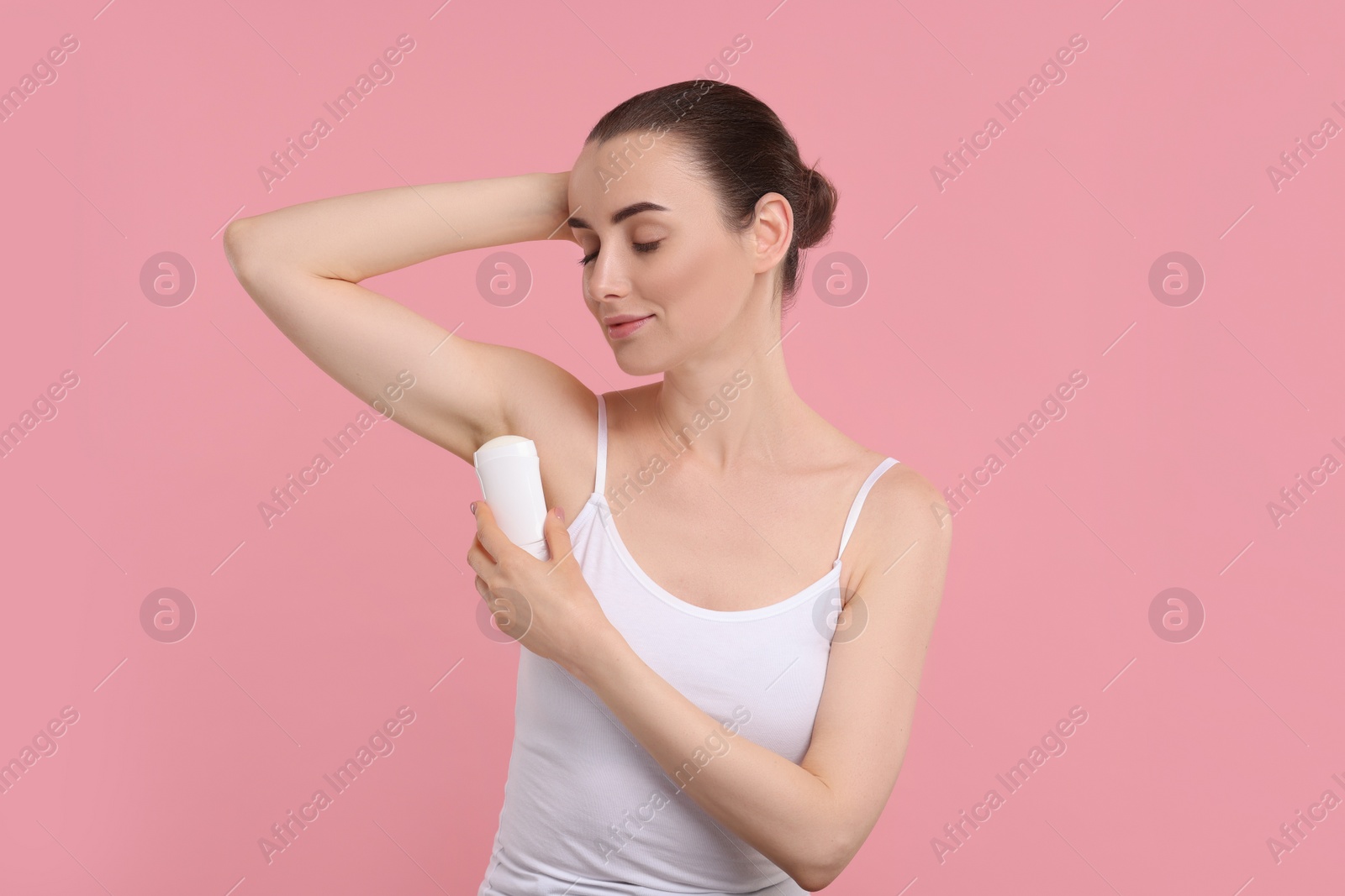 Photo of Beautiful woman applying deodorant on pink background