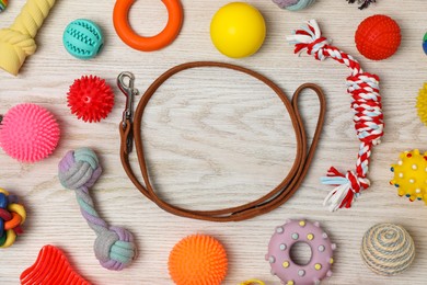 Frame made with dog leash and toys on white wooden background, flat lay. Space for text