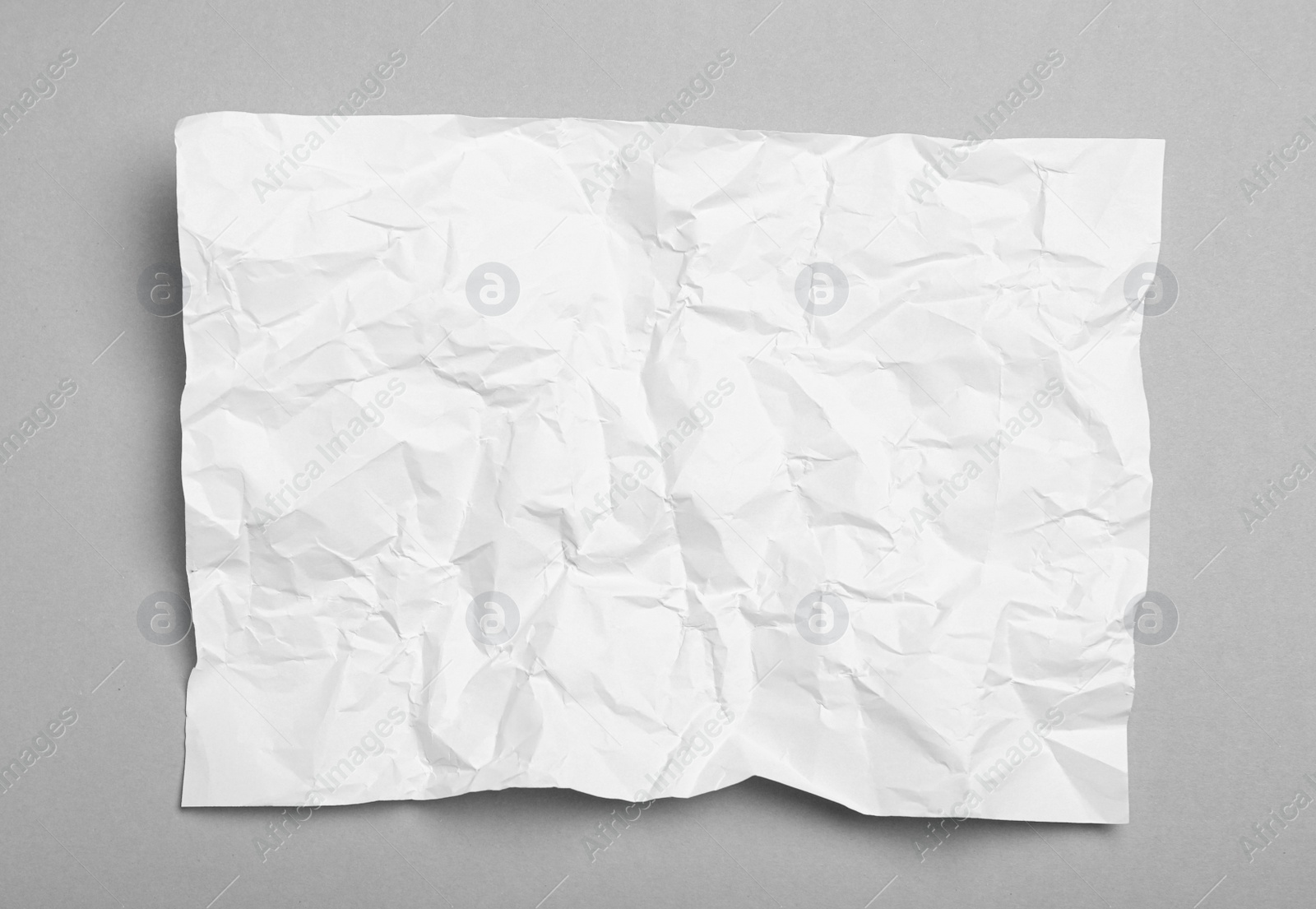 Photo of Sheet of white crumpled paper on grey background, top view