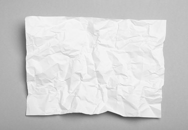 Photo of Sheet of white crumpled paper on grey background, top view