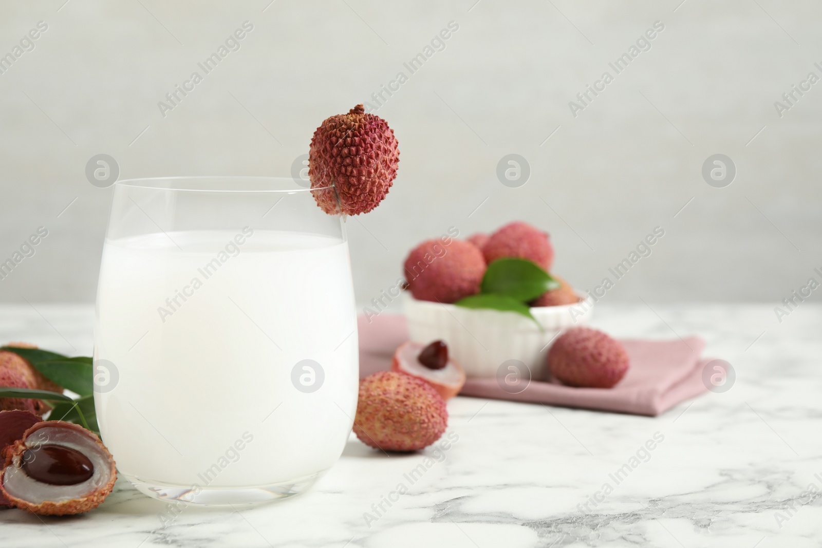 Photo of Lychee juice and fresh fruits on white marble table