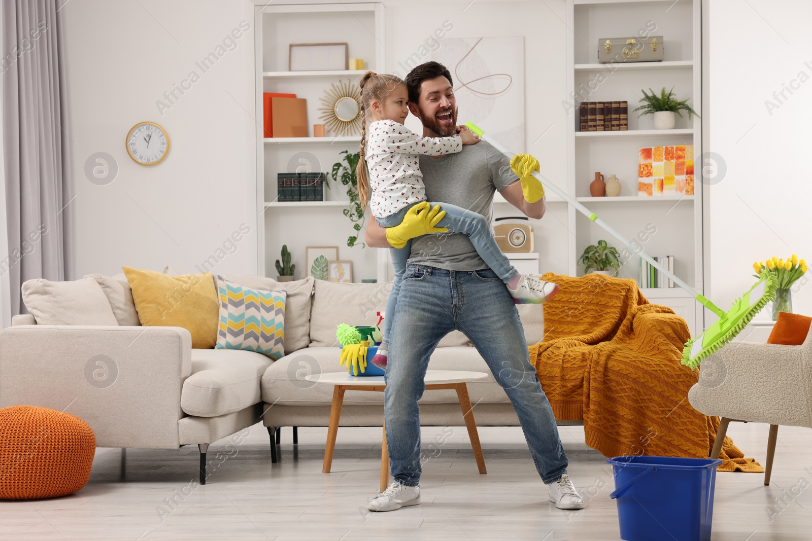 Photo of Spring cleaning. Father and daughter singing while tidying up together at home