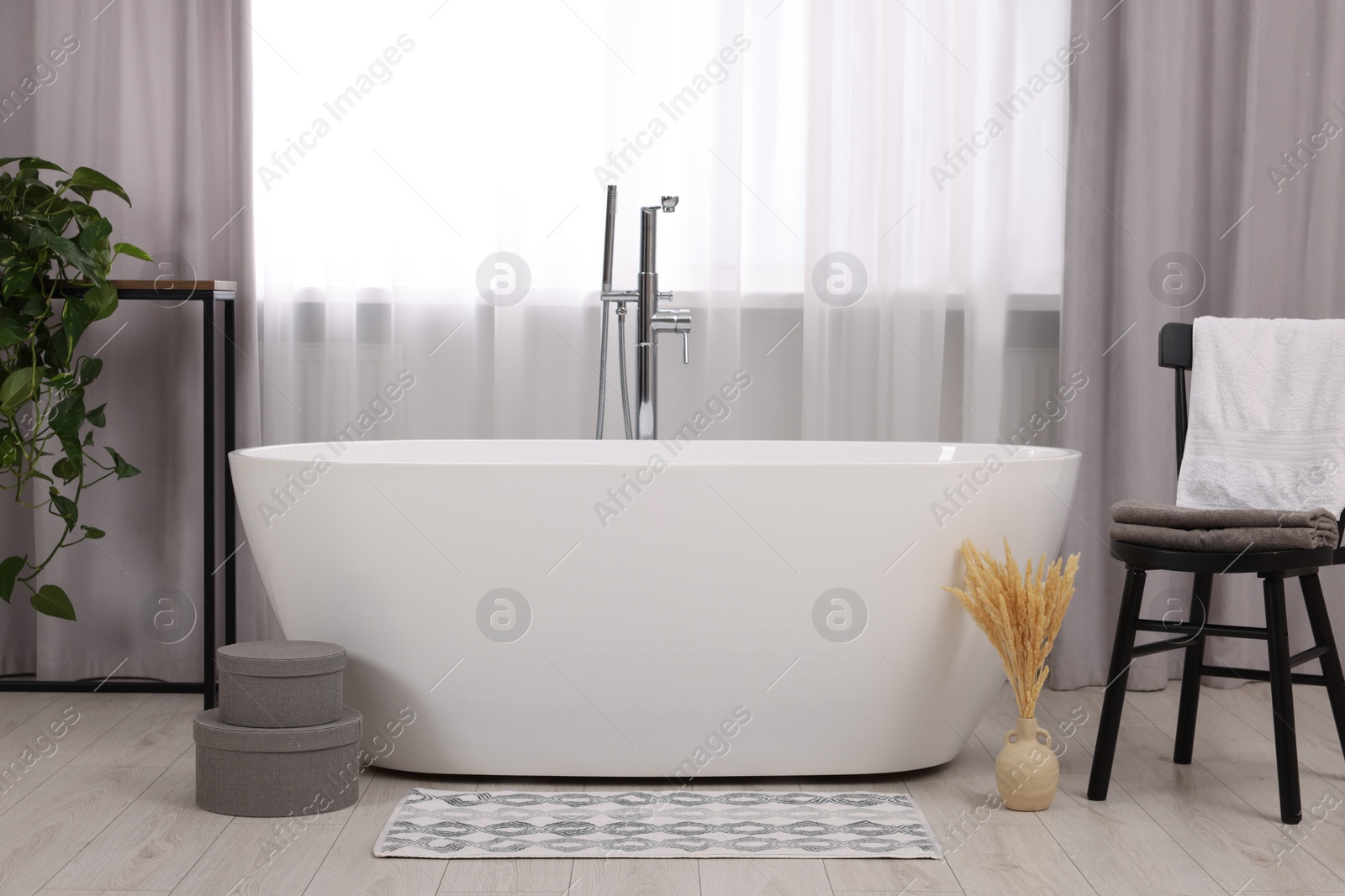 Photo of Stylish bathroom interior with soft bath mat and tub