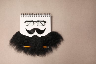 Flat lay composition with artificial moustache and glasses on light brown background, space for text