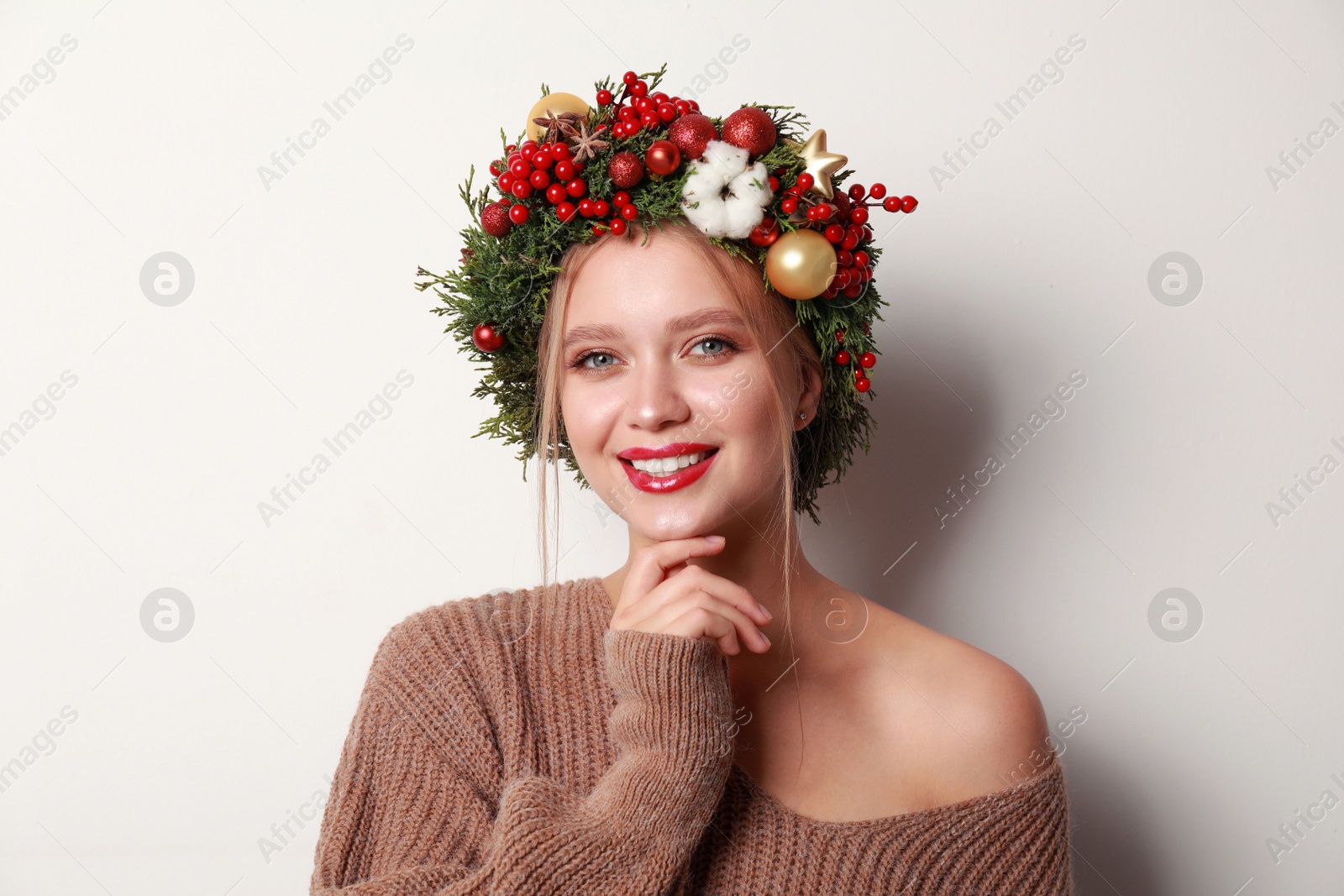 Photo of Beautiful young woman wearing Christmas wreath on white background