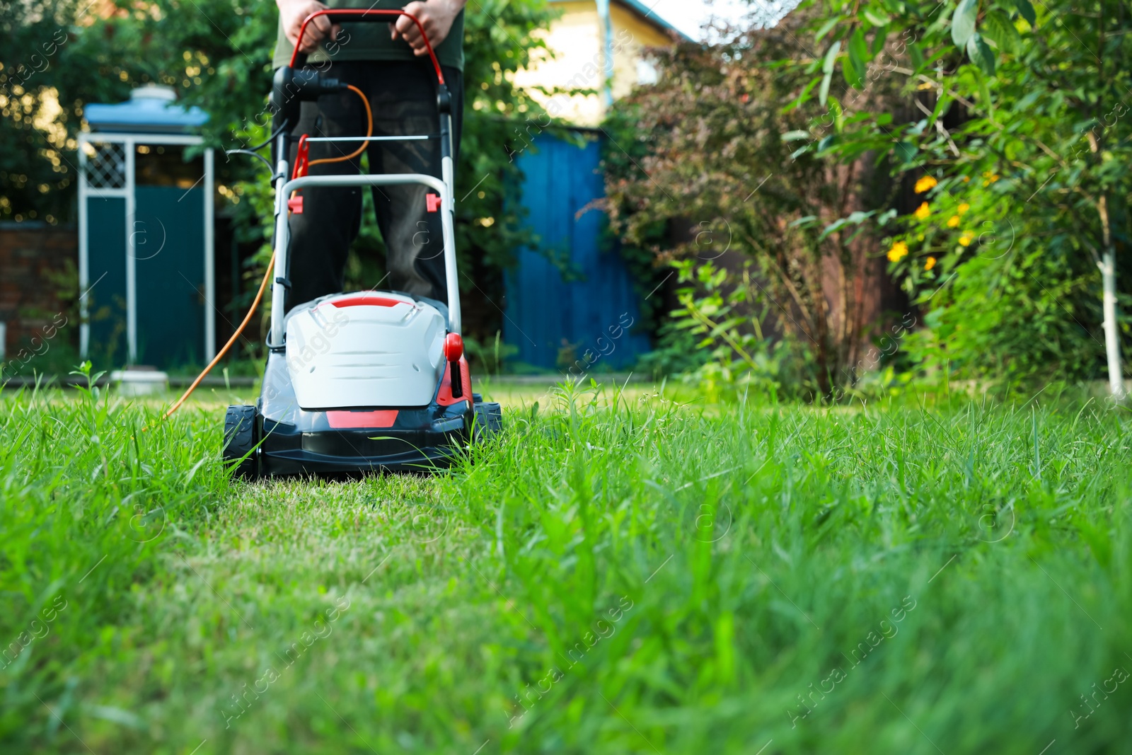 Photo of Man cutting grass with lawn mower in garden, closeup. Space for text