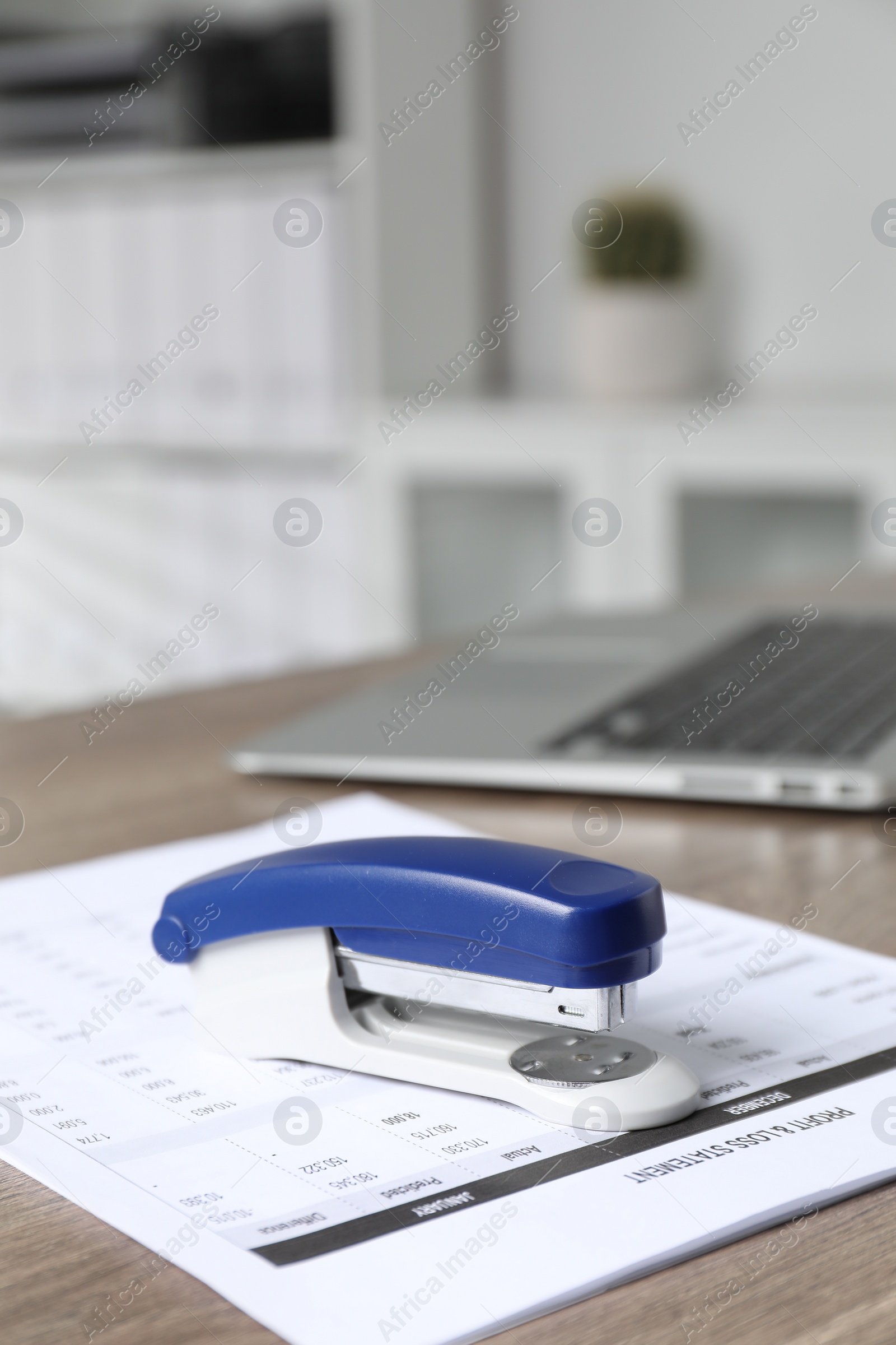 Photo of Bright stapler and document on wooden table indoors