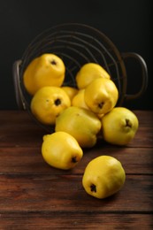Photo of Delicious ripe quinces on wooden table against black background