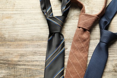 Photo of Different neckties on light wooden table, flat lay. Space for text