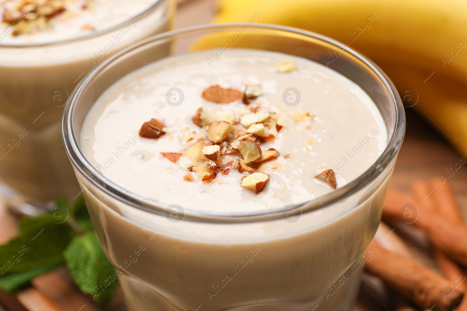 Photo of Tasty banana smoothie with almond and cinnamon on wooden table, closeup