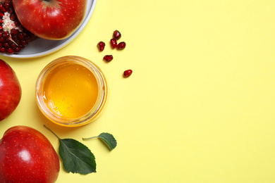 Photo of Honey, apples and pomegranate on yellow background, flat lay with space for text. Rosh Hashanah holiday