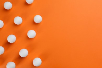 Ping pong balls on orange background, flat lay. Space for text