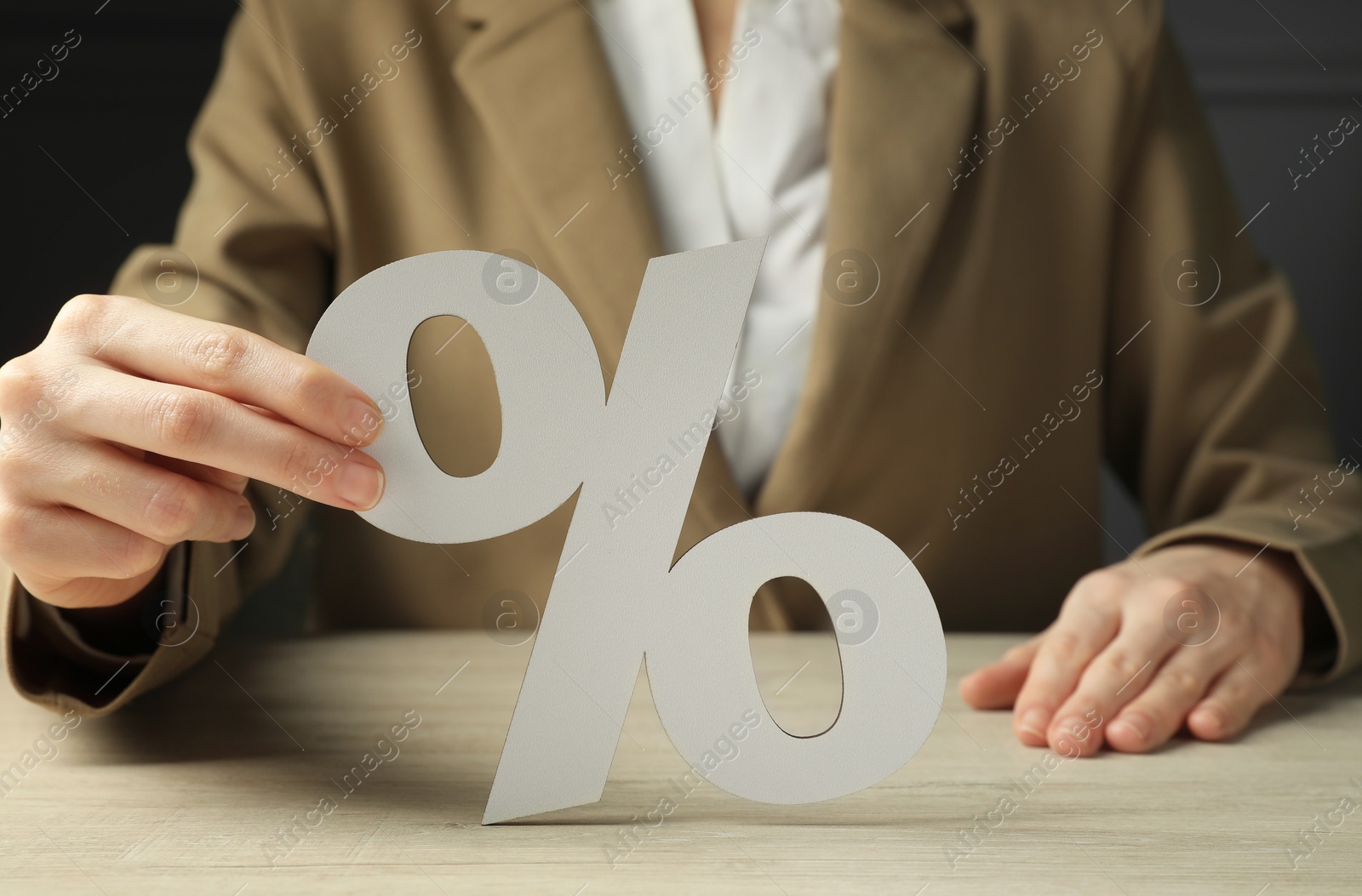 Photo of Woman holding percent sign at wooden table, closeup