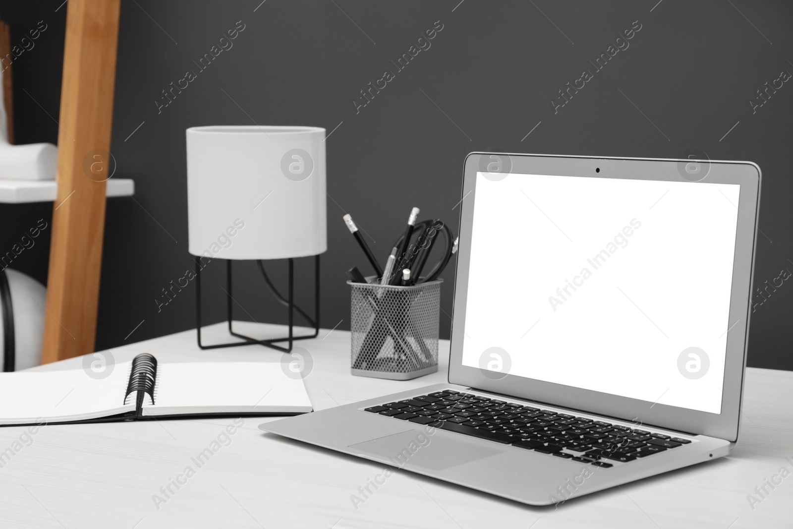 Image of Comfortable workplace at home. Modern laptop with blank screen and stationery on white wooden desk. Mockup for design