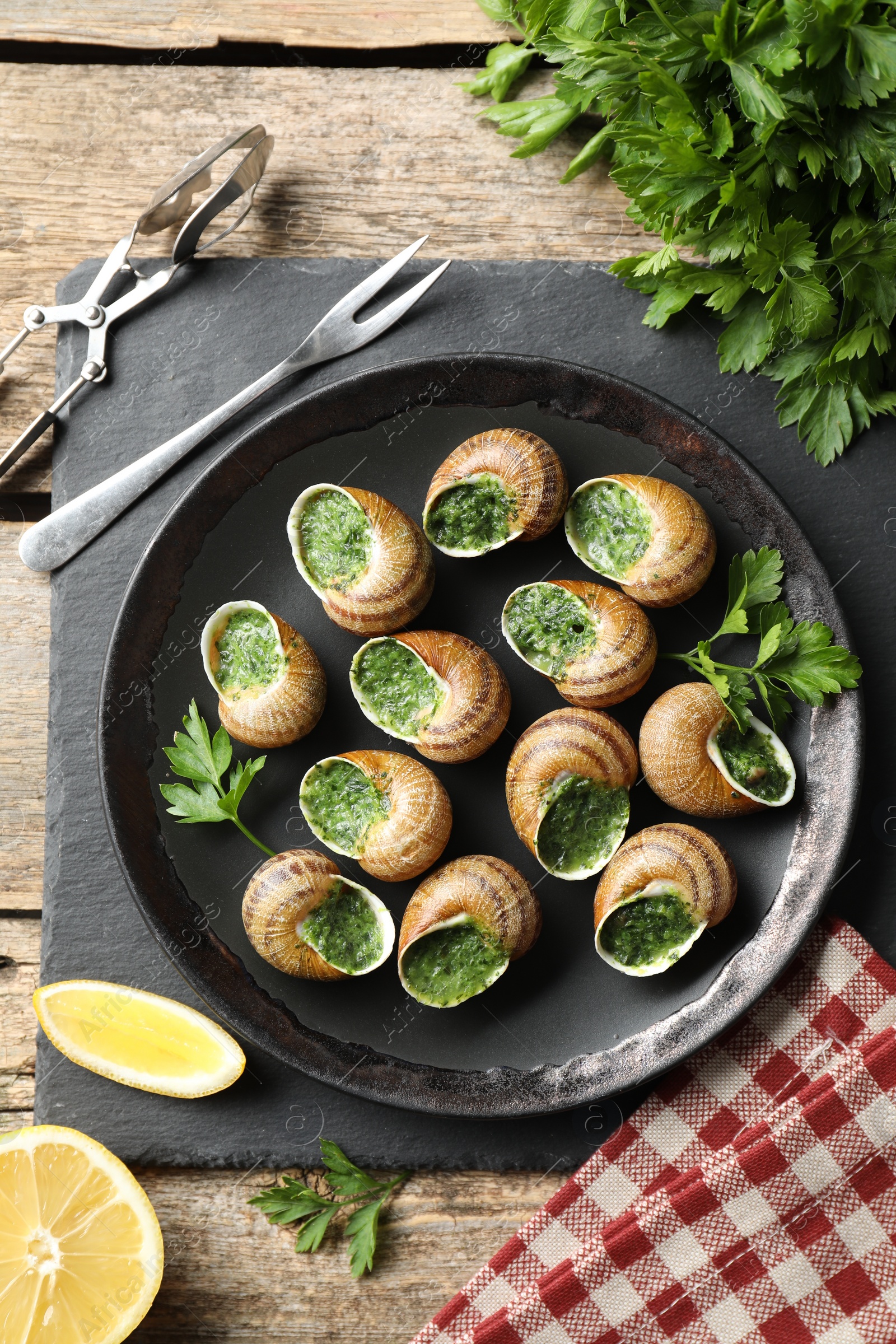 Photo of Delicious cooked snails served on wooden table, flat lay