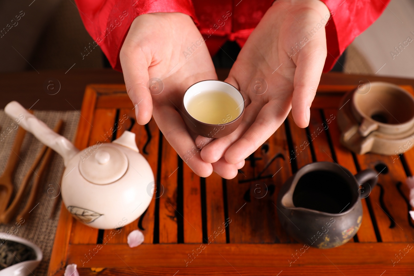 Photo of Master offering cup of freshly brewed tea during traditional ceremony at table, closeup